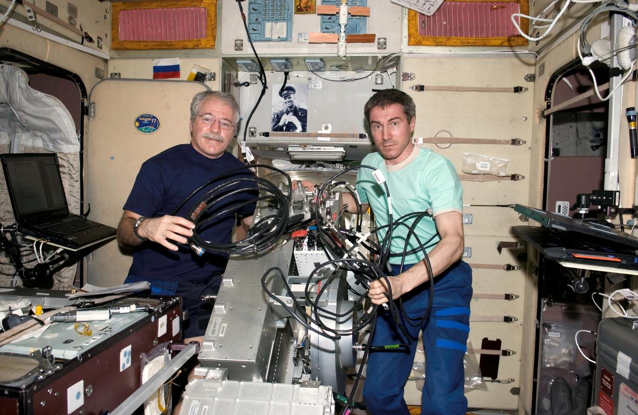 ISS011-E-12495 (7 September 2005) --- Cosmonaut Sergei K. Krikalev (right), Expedition 11 commander representing Russia's Federal Space Agency, and astronaut John L. Phillips, NASA space station science officer and flight engineer, work with the Treadmill Vibration Isolation System (TVIS) during In-Flight Maintenance (IFM) in the Zvezda Service Module of the international space station.
