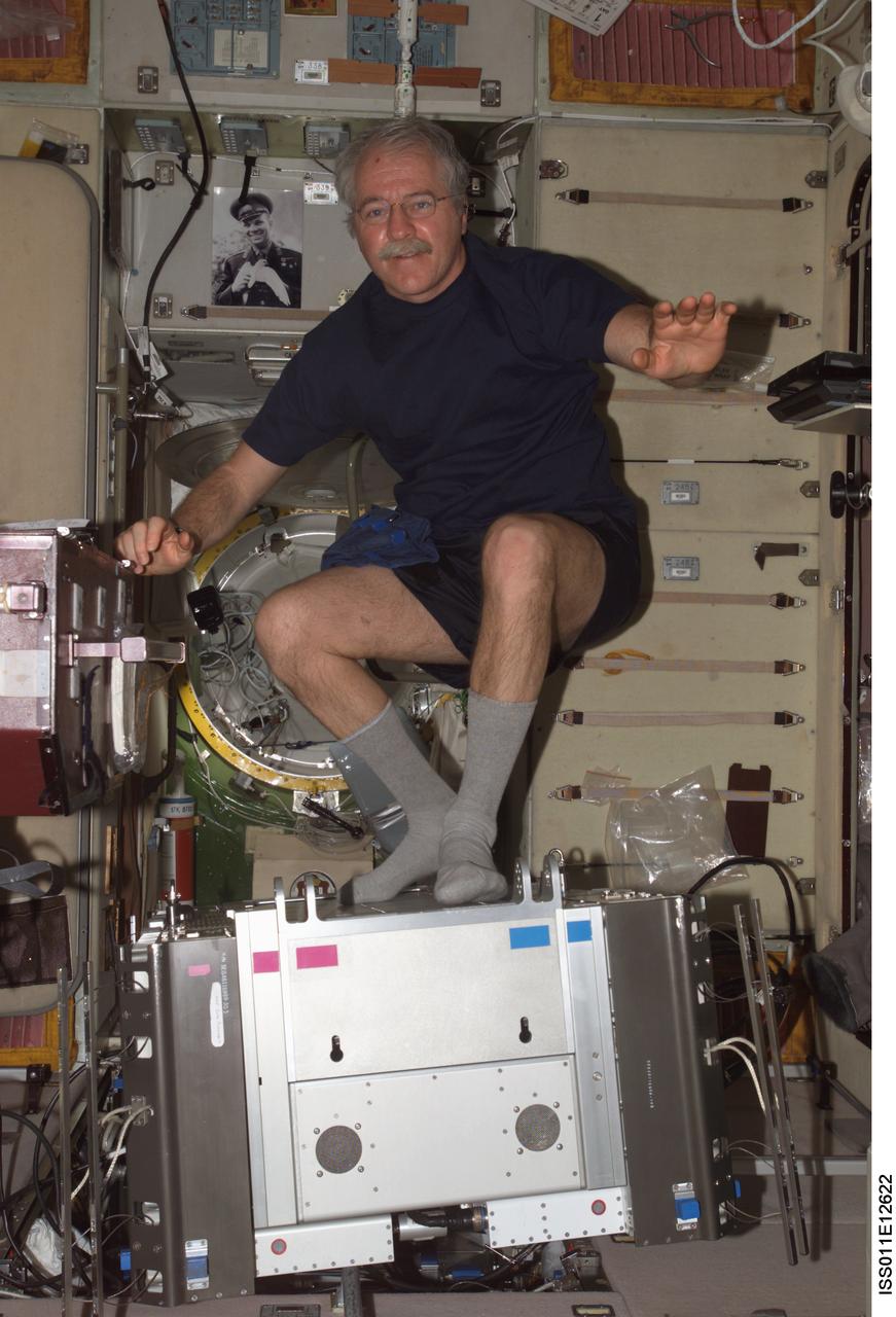 ISS011-E-12622 (7 September 2005) --- Astronaut John L. Phillips, Expedition 11 NASA Space Station science officer and flight engineer, poses with a portion of the Treadmill Vibration Isolation System (TVIS) during In-Flight Maintenance (IFM) in the Zvezda Service Module of the International Space Station.