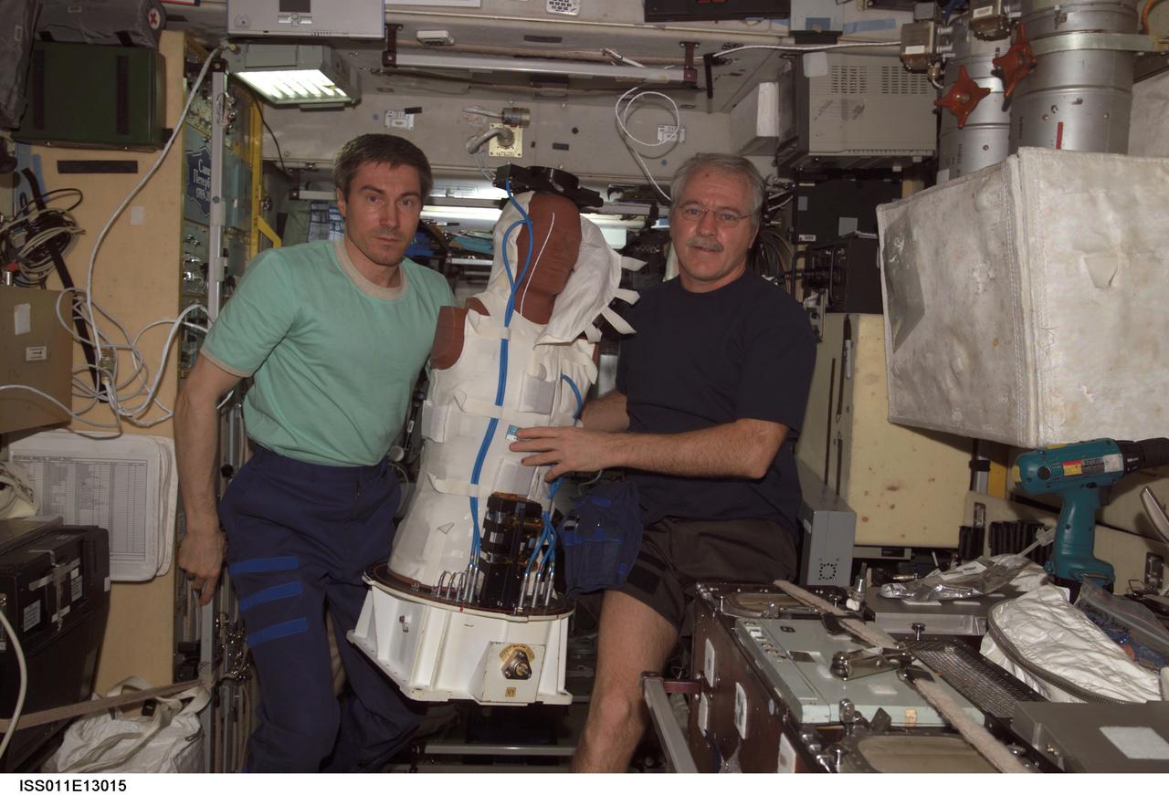 ISS011-E-13015 (14 September 2005) --- Cosmonaut Sergei K. Krikalev (left), Expedition 11 commander representing Russia's Federal Space Agency, and astronaut John L. Phillips, NASA Space Station science officer and flight engineer, hold the European Space Agency (ESA) Matroshka radiation experiment in the Zvezda Service Module of the International Space Station. Matroshka, a human-torso-like device, was retrieved from the exterior of the station during an August spacewalk, for return to Earth. The experiment is designed to better understand the exposure of astronauts, including those making spacewalks, to radiation.