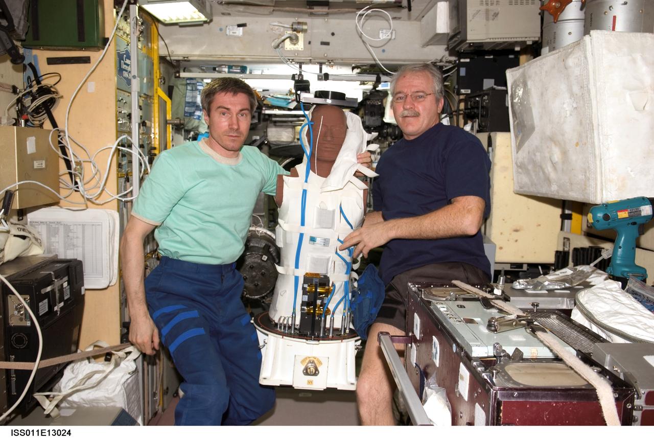 ISS011-E-13024 (14 September 2005) --- Cosmonaut Sergei K. Krikalev (left), Expedition 11 commander representing Russia's Federal Space Agency, and astronaut John L. Phillips, NASA Space Station science officer and flight engineer, hold the European Space Agency (ESA) Matroshka radiation experiment in the Zvezda Service Module of the International Space Station. Matroshka, a human-torso-like device, was retrieved from the exterior of the station during an August spacewalk, for return to Earth. The experiment is designed to better understand the exposure of astronauts, including those making spacewalks, to radiation.