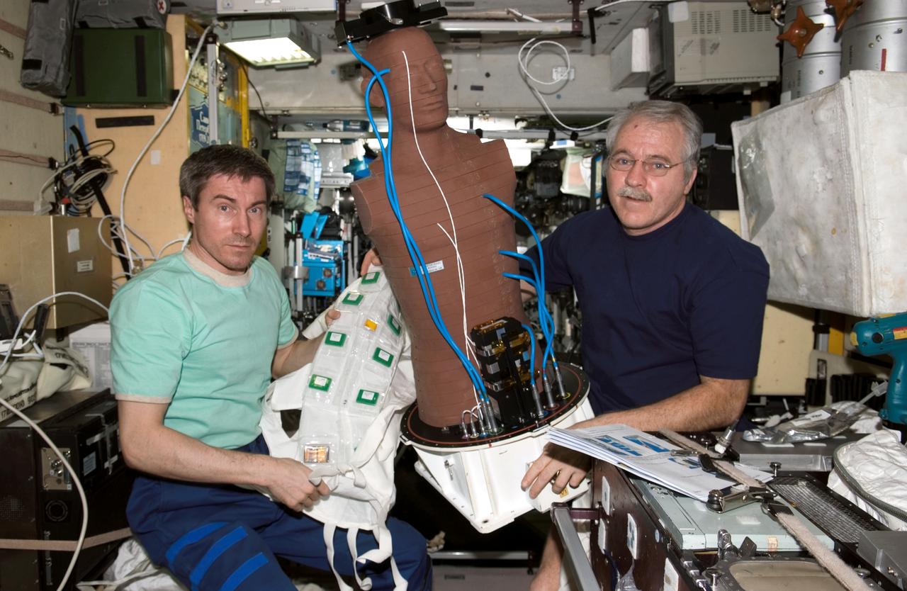 ISS011-E-13025 (14 September 2005) --- Cosmonaut Sergei K. Krikalev (left), Expedition 11 commander representing Russia's Federal Space Agency, and astronaut John L. Phillips, NASA space station science officer and flight engineer, hold the European Space Agency (ESA) Matroshka radiation experiment in the Zvezda Service Module of the international space station. Matroshka, a human-torso-like device, was retrieved from the exterior of the station during an August spacewalk, for return to Earth. The experiment is designed to better understand the exposure of astronauts, including those making spacewalks, to radiation.