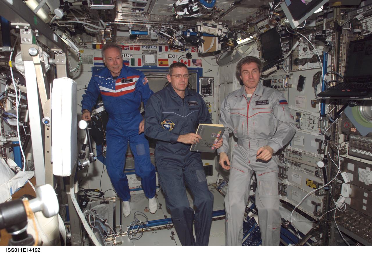 ISS011-E-14192 (8 October 2005) --- Russian Federal Space Agency cosmonaut Sergei K. Krikalev (right), Expedition 11 commander; astronaut William S. McArthur Jr. (center), Expedition 12 commander and NASA science officer; and U. S. Spaceflight Participant Gregory Olsen are pictured in the Destiny laboratory of the international space station following the ceremony of Changing-of-Command from Expedition 11 to Expedition 12.