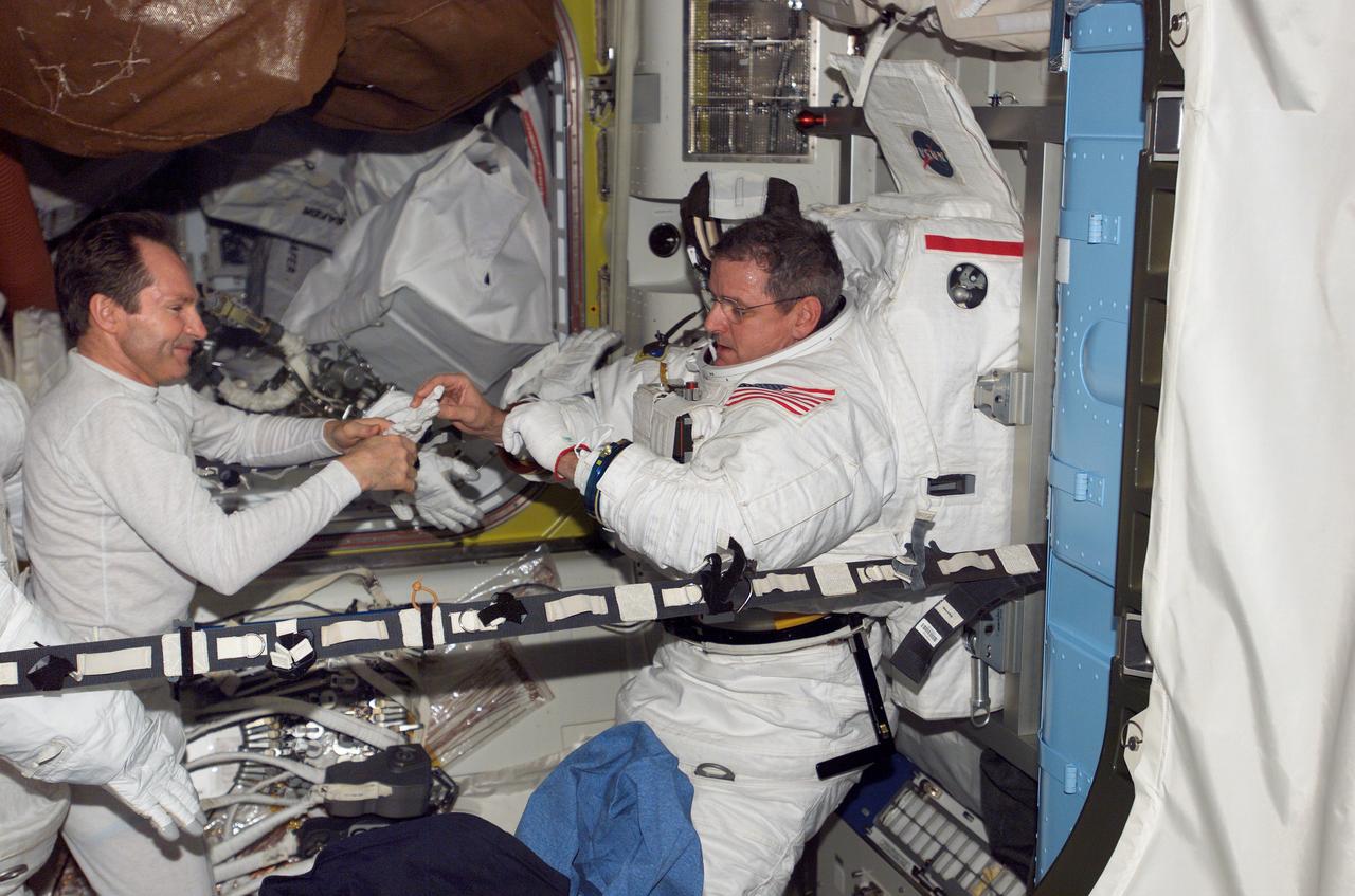ISS012-E-05983 (23 Oct. 2005) --- Astronaut William S. McArthur Jr. (right), Expedition 12 commander and NASA science officer, dons his Extravehicular Mobility Unit (EMU) spacesuit in the Quest Airlock of the international space station. Cosmonaut Valery I. Tokarev, flight engineer representing Russia's Federal Space Agency, assisted McArthur. When the Expedition 12 crew performs its first scheduled day of spacewalking on Nov. 7, it will be attired in the NASA EMU.