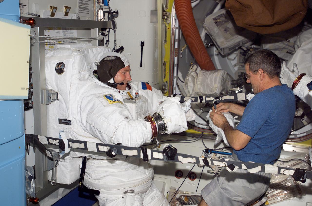 ISS012-E-06011 (23 Oct. 2005) --- Cosmonaut Valery I. Tokarev (left), Expedition 12 flight engineer representing Russia's Federal Space Agency, dons his Extravehicular Mobility Unit (EMU) spacesuit in the Quest Airlock of the international space station. Astronaut William S. McArthur Jr., commander and NASA science officer, assisted Tokarev. When the Expedition 12 crew performs its first scheduled day of spacewalking on Nov. 7, it will be attired in the NASA EMU.