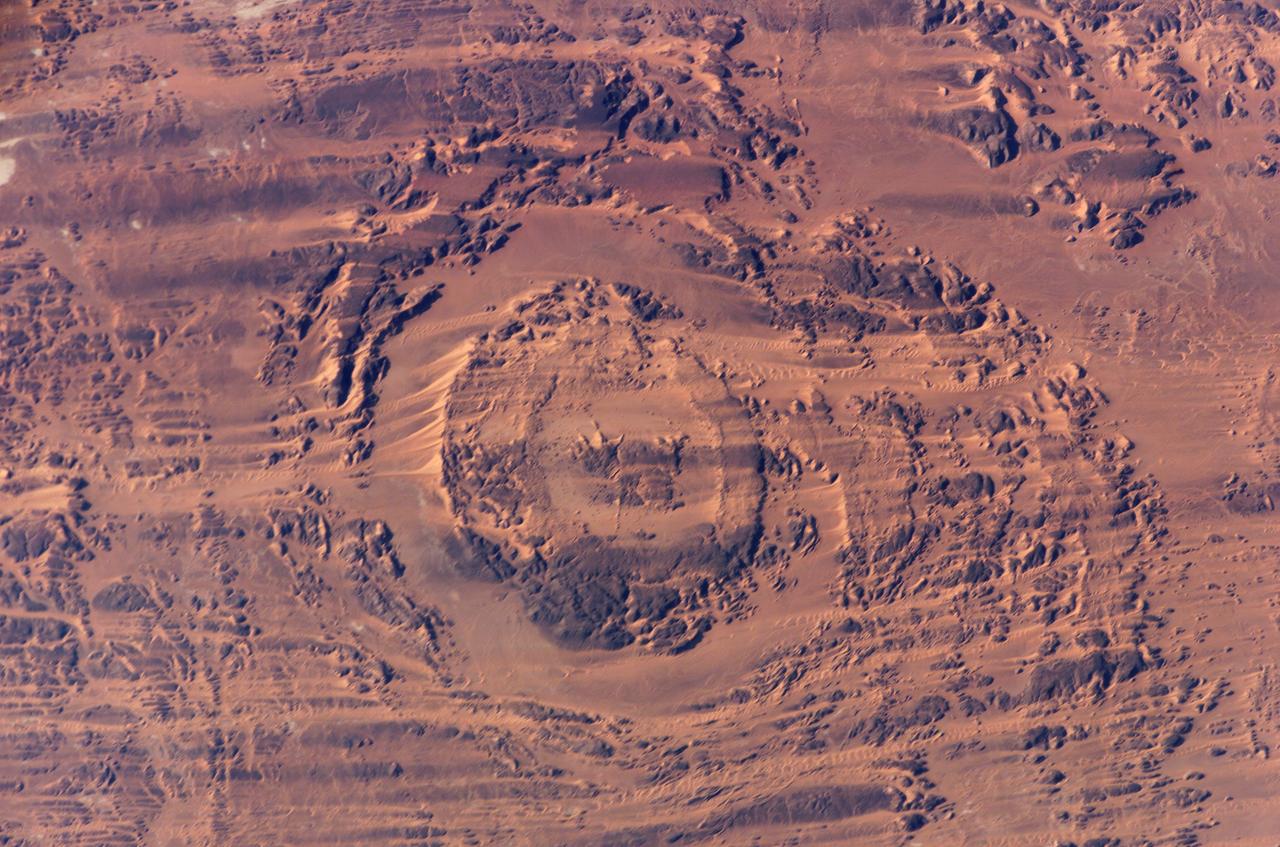 ISS012-E-09639 (29 Nov. 2005) --- The impact of an asteroid or comet several hundred million years ago, according to scientists, left scars in the landscape that are still visible in this International Space Station/Expedition 12 picture of an area in the Sahara Desert of northern Chad. The concentric ring structure is the Aorounga impact crater, with a diameter of about 17 kilometers (10.5 miles). The original crater was buried by sediments, which were then partially eroded to reveal the current ring-like appearance.  Scientists note a number of valleys cut by thousands of years of wind erosion.  The area shown is centered at approximately 19.1 degrees north latitude and 19.3 degrees east longitude.