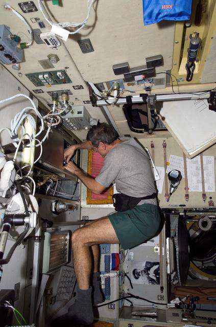 NASA image: McArthur prepares to clean a ventilation filter screen inside the SM during Expedition 12