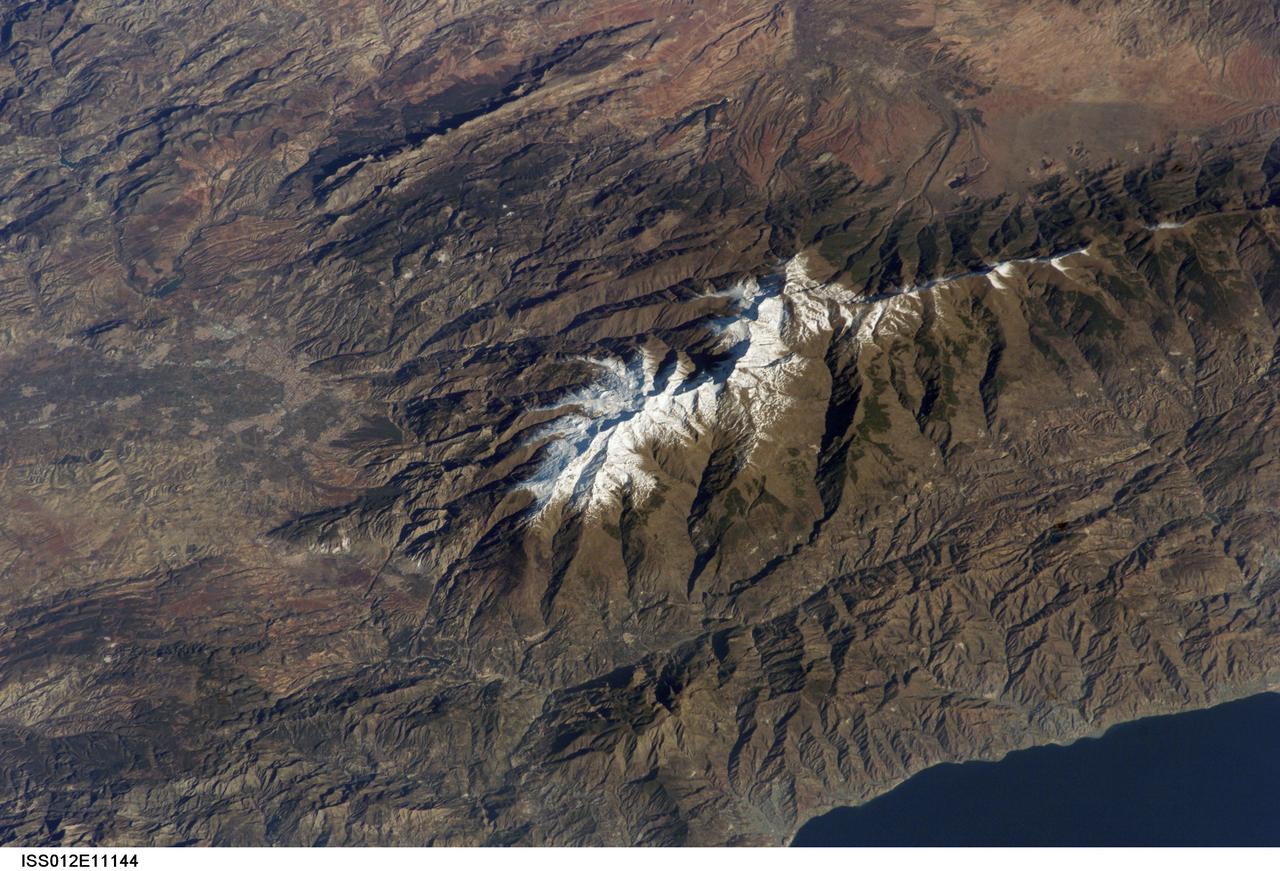 ISS012-E-11144 (11 Dec. 2005) --- Sierra Nevada, Spain is featured in this image photographed by an Expedition 12 crew member on the International Space Station. According to scientists, the Sierra Nevada, part of the Betic Cordillera of southern Spain, was formed during the Alpine Orogeny (or mountain-building event) that also formed the European Alps to the east and the Atlas Mountains of northern Africa across the Mediterranean Sea to the south. The Sierra as observed today formed during the Tertiary Period (65 to 1.8 million years ago) during collision of the African and Eurasian continental plates. The former Tethys Sea also closed during this time period, the scientists say, and the Mediterranean Sea is the largest surviving remnant basin of the ancient Tethys. The Sierra Nevada in the Granada province of Spain is perhaps the southernmost skiing location in all of Europe. Veleta Peak, at an elevation of 3,398 meters above sea level, is a popular destination for skiers and snowboarders. The rapid transition from lofty ski runs to Mediterranean beaches within a few hours’ drive has made the Sierra Nevada region popular for both outdoor and urban tourism. This photograph depicts the Veleta Peak region of the range and illustrates the sharp contrast between the snow capped mountains, adjacent dry lowlands to the west and north, and the Mediterranean Sea to the south.