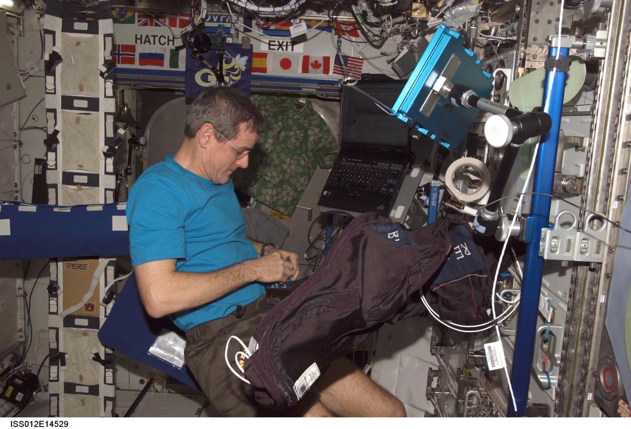 ISS012-E-14529 (10 Jan. 2006) --- Astronaut William S. (Bill) McArthur, Expedition 12 commander and NASA space station science officer, performs Foot/Ground Reaction Forces During Spaceflight (FOOT) experiment set-up operations in the Destiny laboratory of the International Space Station. Foot Ground Interface Flight Calibration Unit (FGI-FCU) is visible upper right and the Lower Extremity Monitoring Suit (LEMS) is visible in the foreground.