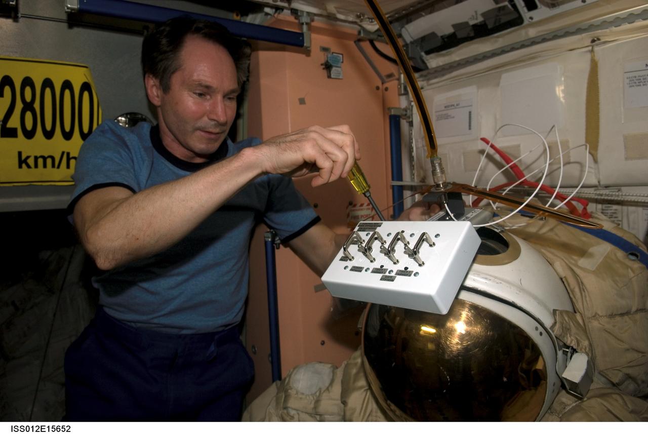 ISS012-E-15652 (24 Jan. 2006) --- In the Unity node of the International Space Station, cosmonaut Valery I. Tokarev, Expedition 12 flight engineer representing Russia's Federal Space Agency, puts finishing touches on an old Russian Orlan spacesuit that will be released by hand from the space station during a spacewalk Feb. 3, 2006. Outfitted with a special radio transmitter and other gear, the spacesuit comprises a Russian experiment called SuitSat. It will fly free from the station as a satellite in orbit for several weeks of scientific research and radio tracking, including communications by amateur radio operators. Eventually, it will enter the atmosphere and be destroyed.