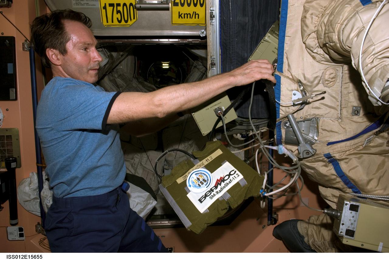 ISS012-E-15655 (24 Jan. 2006) --- In the Unity node of the International Space Station, cosmonaut Valery I. Tokarev, Expedition 12 flight engineer representing Russia's Federal Space Agency, puts finishing touches on an old Russian Orlan spacesuit that will be released by hand from the space station during a spacewalk Feb. 3, 2006. Outfitted with a special radio transmitter and other gear, the spacesuit comprises a Russian experiment called SuitSat. It will fly free from the station as a satellite in orbit for several weeks of scientific research and radio tracking, including communications by amateur radio operators. Eventually, it will enter the atmosphere and be destroyed.
