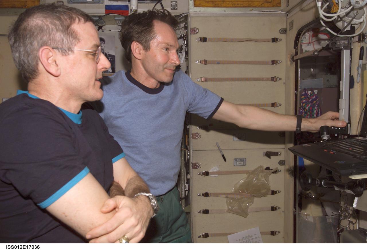 ISS012-E-17036 (23 Jan. 2006) --- Astronaut William S. (Bill) McArthur (foreground), Expedition 12 commander and NASA space station science officer, and cosmonaut Valery I. Tokarev, flight engineer representing Russia's Federal Space Agency, watch the contents of a compact disk at a work station in the Zvezda Service Module of the International Space Station. The compact disk was in the Radioskaf (SuitSat) package delivered to the station by a Progress spacecraft.