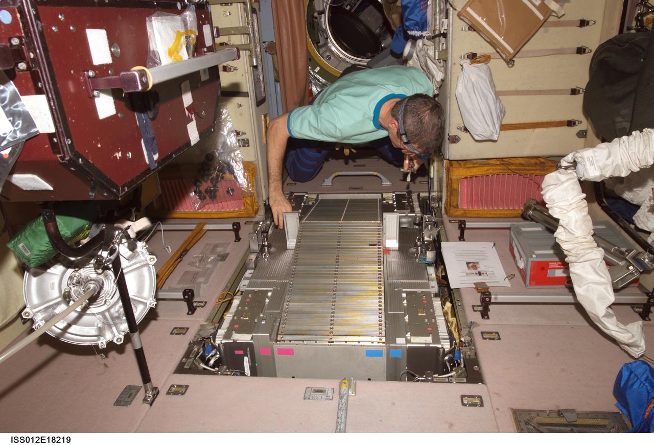 ISS012-E-18219 (13 Feb. 2006) --- Astronaut William S. (Bill) McArthur, Expedition 12 commander and NASA space station science officer, works with the Treadmill Vibration Isolation System (TVIS) during in-flight maintenance (IFM) in the Zvezda Service Module of the International Space Station.