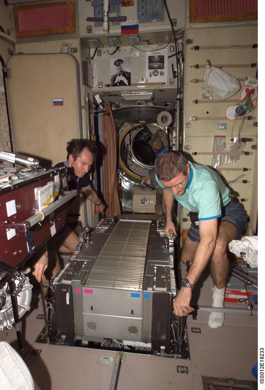 ISS012-E-18233 (14 Feb. 2006) --- Astronaut William S. (Bill) McArthur (right), Expedition 12 commander and NASA space station science officer, and cosmonaut Valery I. Tokarev, flight engineer representing Russia's Federal Space Agency, work with the Treadmill Vibration Isolation System (TVIS) during in-flight maintenance (IFM) in the Zvezda Service Module of the International Space Station.