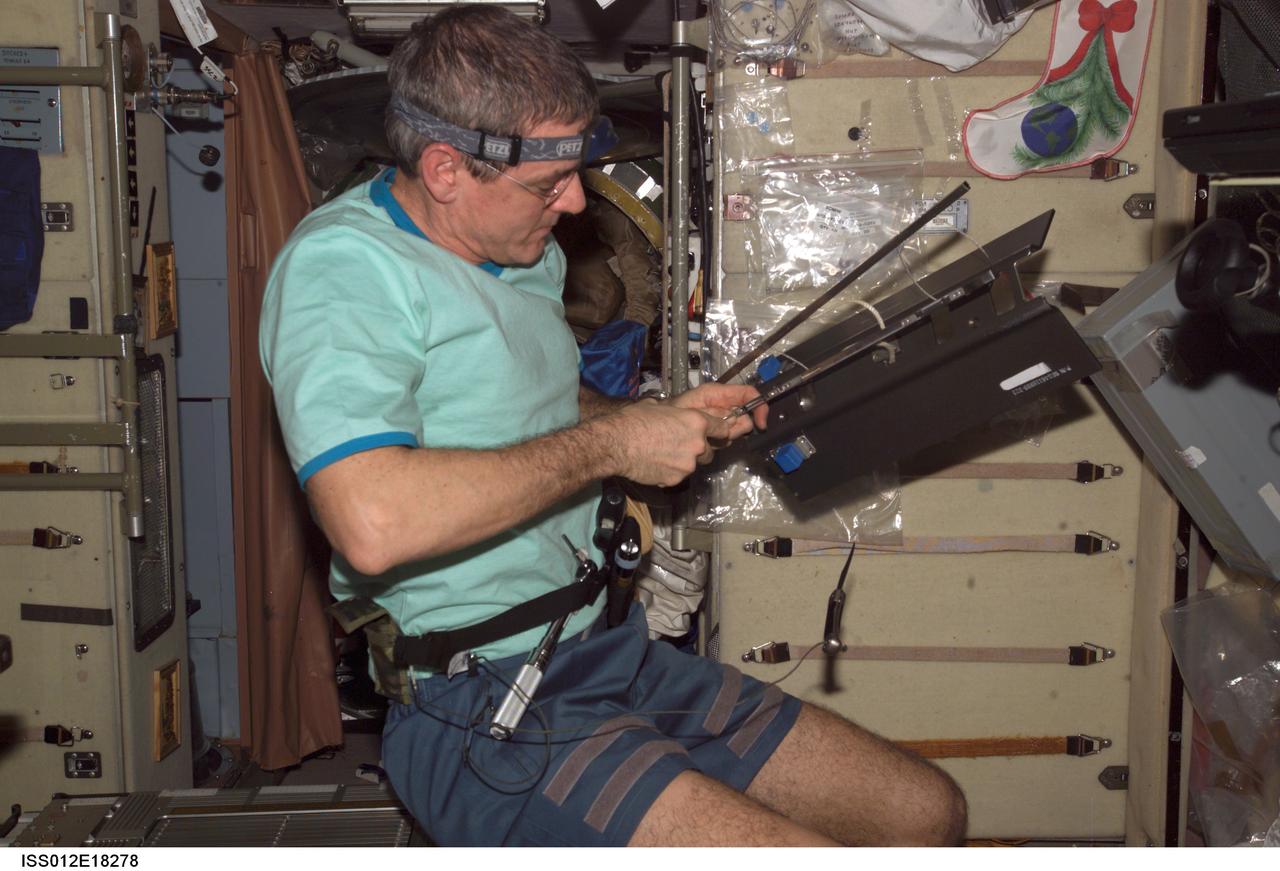 ISS012-E-18278 (14 Feb. 2006) --- Astronaut William S. (Bill) McArthur, Expedition 12 commander and NASA space station science officer, works with a portion of the Treadmill Vibration Isolation System (TVIS) during in-flight maintenance (IFM) in the Zvezda Service Module of the International Space Station.