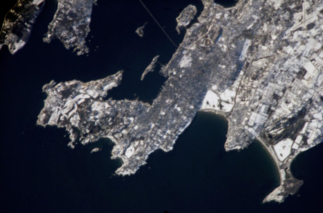 ISS012-E-19051 (4 March 2006) --- Newport, R.I., is featured in this image photographed by an Expedition 12 crew member on the International Space Station. Newport is well-known as a summer destination, but winter snow blankets the city in this image. One of the first settlements by Europeans in the Americas, the region was initially settled by colonists seeking religious freedom denied them in Europe, but over time some of them perceived a need to escape the strictures of the dominant Puritan faith. Newport, founded in 1639, became a bastion of the Baptist faith and exemplified one of the basic precepts of the United States Constitution – separation of church and state. Throughout the 17th and 18th centuries, Newport consolidated its position as one of the premier ports of the United States. The 19th and early 20th centuries saw a decline in commercial shipping at Newport and its rebirth as a recreational destination. Many of the leading industrialist families of the time, such as the Vanderbilts, built grand summer mansions in Newport that are now open to visitors. The United States Navy has also had a strong presence in the Newport area since 1869, exemplified by the establishment of the Naval War College in 1884 (image top center). The College still serves as an educational institution for naval officers. The gray-brown metropolitan area of Newport is thrown into sharp contrast by the surrounding snow-covered open fields and rural areas to the east and southwest. The Clairborne Pell (also known as Newport) Bridge connects Jamestown, R.I. on Conanicut Island to Newport at image top. The main span of this suspension bridge is 1600 feet (485 meters) long and crosses the East Passage of Narragansett Bay. The Sachuest Point National Wildlife Refuge (image lower right) supports over 200 bird species, including the largest winter harlequin duck population on the East Coast.