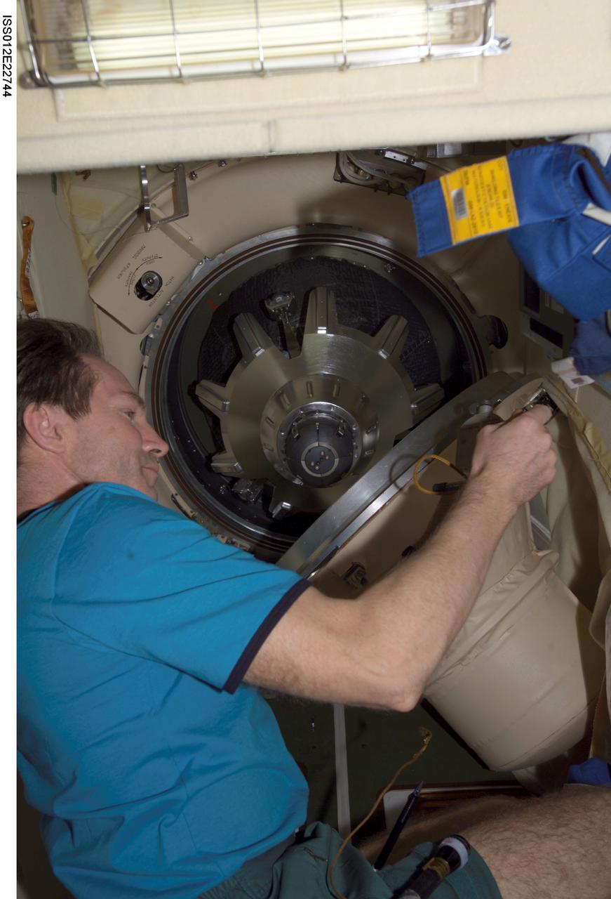 ISS012-E-22744 (23 Dec. 2005) --- Cosmonaut Valery I. Tokarev, Expedition 12 flight engineer representing Russia's Federal Space Agency, opens the Progress transfer hatch on the International Space Station. Progress 20 docked to the Pirs Docking Compartment at 1:46 p.m. (CST) on Dec. 23 as the station flew approximately 220 statute miles above the Atlantic off the east coast of South America. Progress delivered 2.8 tons of supplies, gifts, food, water, fuel and equipment to the crew members onboard the station.