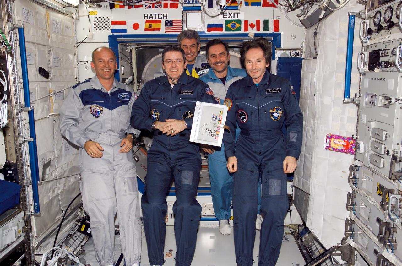 ISS012-E-24274 (7 April 2006) --- The crewmembers onboard the International Space Station pose for a group photo during the ceremony of Changing-of-Command from Expedition 12 to Expedition 13 in the Destiny laboratory of the International Space Station. From the left (front row) are astronauts Jeffrey N. Williams, Expedition 13 NASA space station science officer and flight engineer; William S. (Bill) McArthur, Jr., Expedition 12 commander and NASA space station science officer; and cosmonaut Valery I. Tokarev, Expedition 12 flight engineer representing Russia's Federal Space Agency. From the left (back row) are Brazilian Space Agency astronaut Marcos C. Pones and cosmonaut Pavel V. Vinogradov, Expedition 13 commander representing Russia's Federal Space Agency. The "ship's log" floats freely in the foreground.