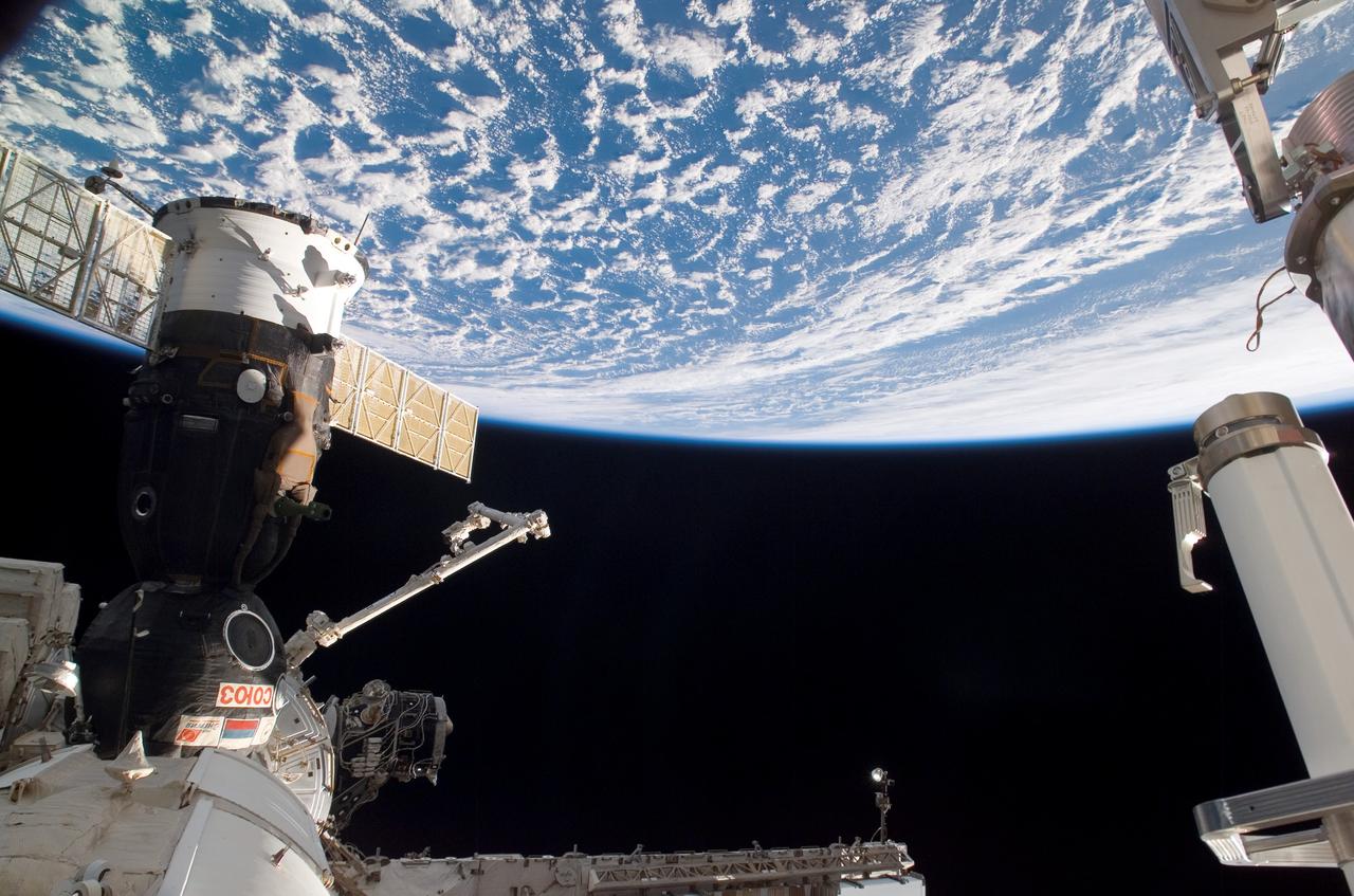 ISS013-E-08178 (19 April 2006) --- A Soyuz spacecraft, docked to the International Space Station, and the Canadarm2 are featured in this image photographed by an Expedition 13 crewmember from a station window. Earth's horizon and the blackness of space provided the backdrop for this scene.