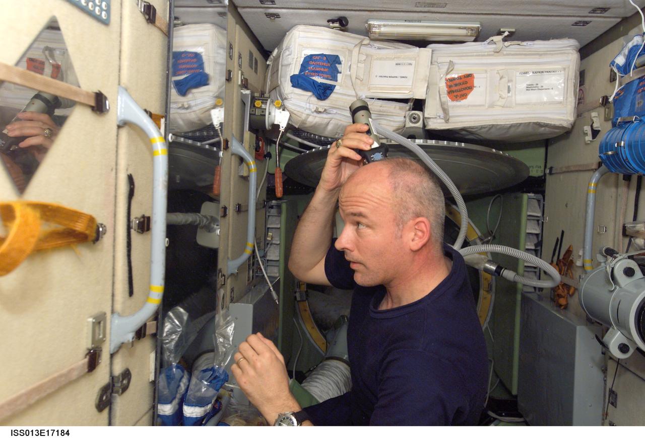 ISS013-E-17184 (9 May 2006) --- Astronaut Jeffrey N. Williams, Expedition 13 NASA space station science officer and flight engineer, trims his hair in the Zarya module of the International Space Station. Williams used hair clippers fashioned with a vacuum device to garner freshly cut hair.