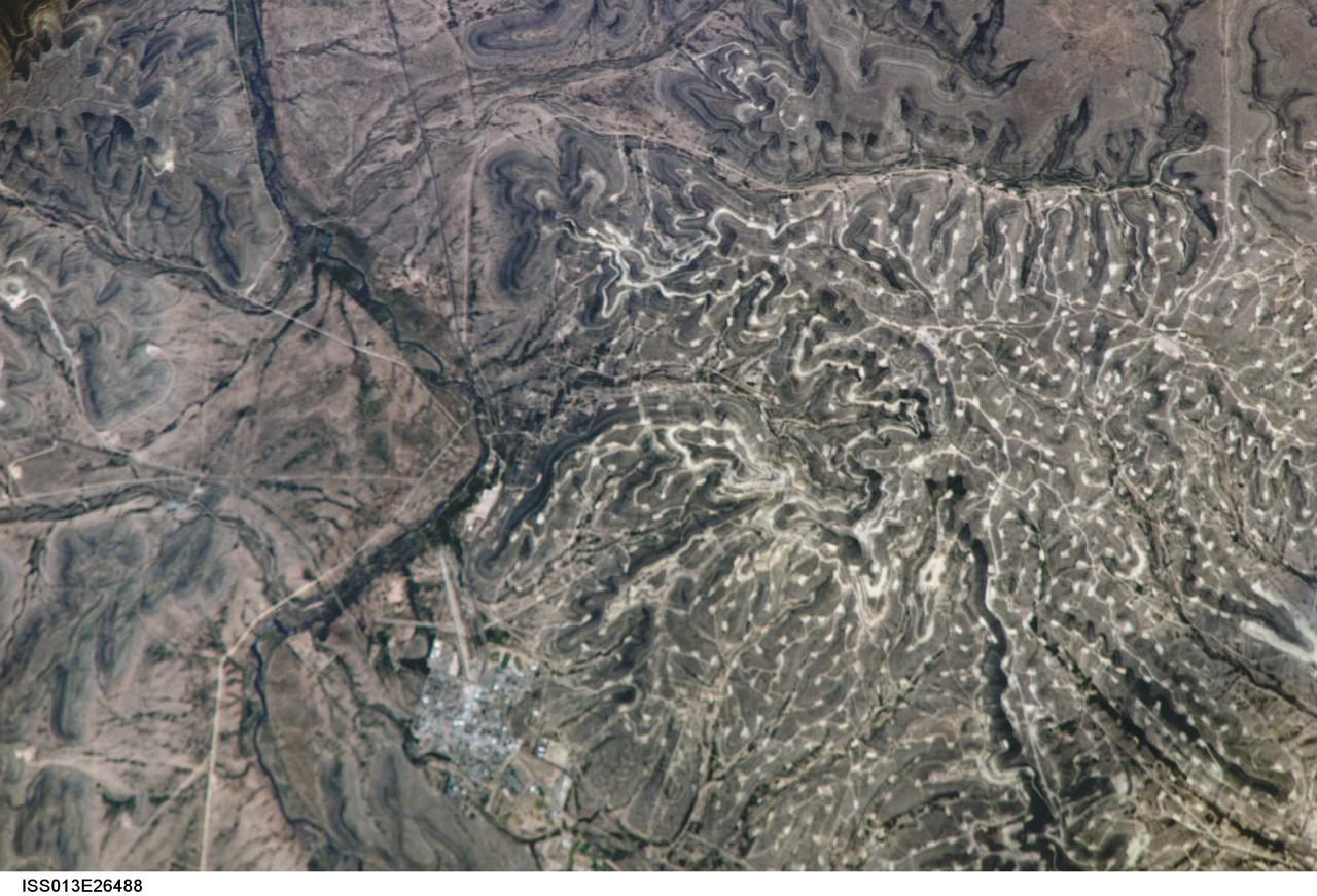 ISS013-E-26488 (25 May 2006) --- Yates Oilfield, west Texas is featured in this image photographed by an Expedition 13 crewmember on the International Space Station. The Permian Basin of west Texas and southeastern New Mexico is one of the most productive petroleum provinces of North America. The Basin is a large depression in the Precambrian bedrock surface along the southern edge of the North American craton, or oldest bedrock core of the continent. The Yates Oil Field is marked in this image by numerous white well locations and petroleum infrastructure dotting the layered sedimentary rocks of the Permian Basin. The Pecos River bed borders the oil field to the east-northeast. The Yates Field started petroleum production in 1926, and by 1995 had produced over 2 billion barrels of oil.