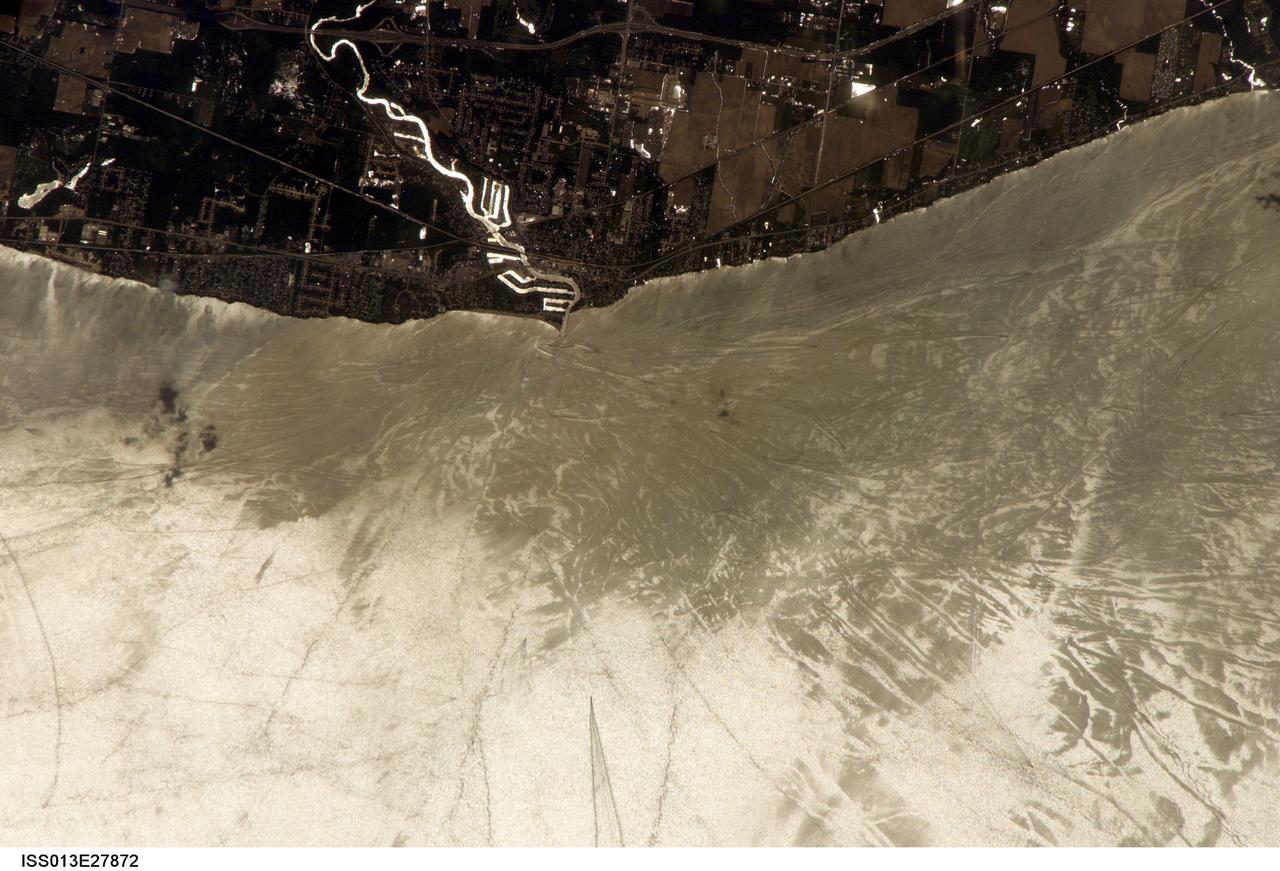ISS013-E-27872 (28 May 2006) --- Considerable sunglint emphasizes features on Lake Erie in this image photographed by an Expedition 13 crewmember on the International Space Station. This detailed, south-looking image shows features on the surface of Lake Erie, about 30 miles west of Cleveland, Ohio. This view shows the Vermilion River in strong sunglint. The angular water bodies along the river are likely marinas. The main part of the image show numerous ship wakes in the zone of partial glint around the disk of the Sun's reflection point. The wakes radiate from the mouth of the Vermilion River, with many of them heading northwest in the direction of Detroit, Michigan.