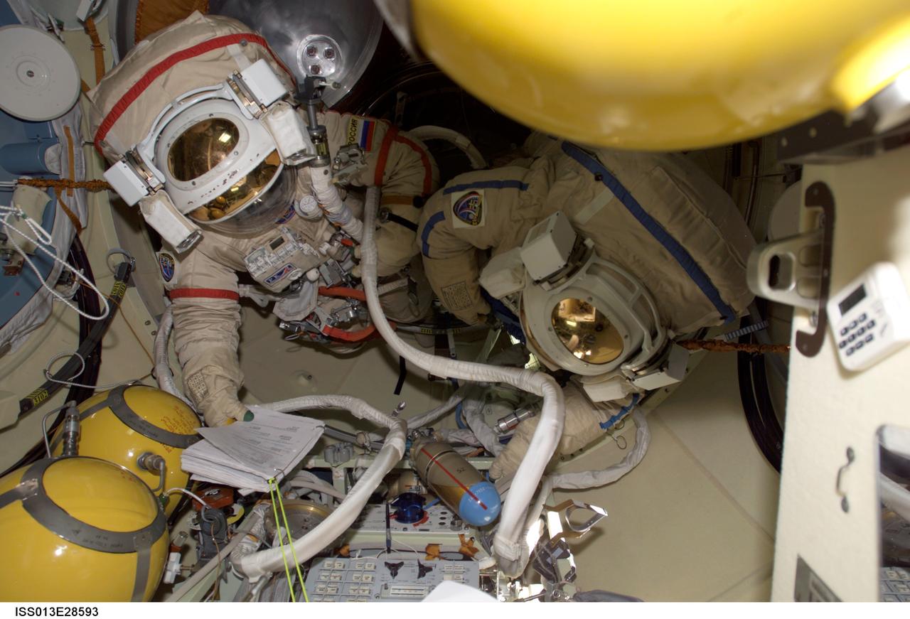 ISS013-E-28593 (30 May 2006) --- Cosmonaut Pavel V. Vinogradov, Expedition 13 commander representing Russia's Federal Space Agency, and astronaut Jeffrey N. Williams, NASA space station science officer and flight engineer, attired in Russian Orlan spacesuits, look over a checklist in the Pirs Docking Compartment of the International Space Station as they prepare for a spacewalk scheduled for June 1.