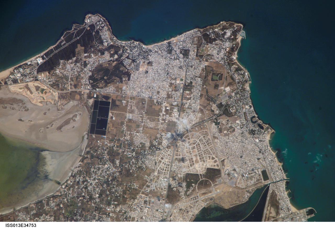 ISS013-E-34753 (8 June 2006) --- Carthage, Tunisia is featured in this image photographed by an Expedition 13 crewmember on the International Space Station. The favorable location of the ancient city of Carthage is clear in this image. Embayments along the coastline provided ready access to the Gulf of Tunis/Mediterranean Sea to the east and southeast. Docks along the coastline (lower right) support the shipping industry. Modern Carthage is a wealthy suburb of the Tunis metropolitan area (the center of which is located to the southwest of the image), as evidenced by dense concentrations of white building rooftops in residential subdivisions to the north and south of the ancient city location. Large tracts of new developments appear to be in progress along the curving, light colored roadways to the southwest of the historical city (lower center). The green shallow waters of an evaporating saline lake are visible at image left ? several such lakes are present in Tunisia and are centers for bird watching-related tourism.