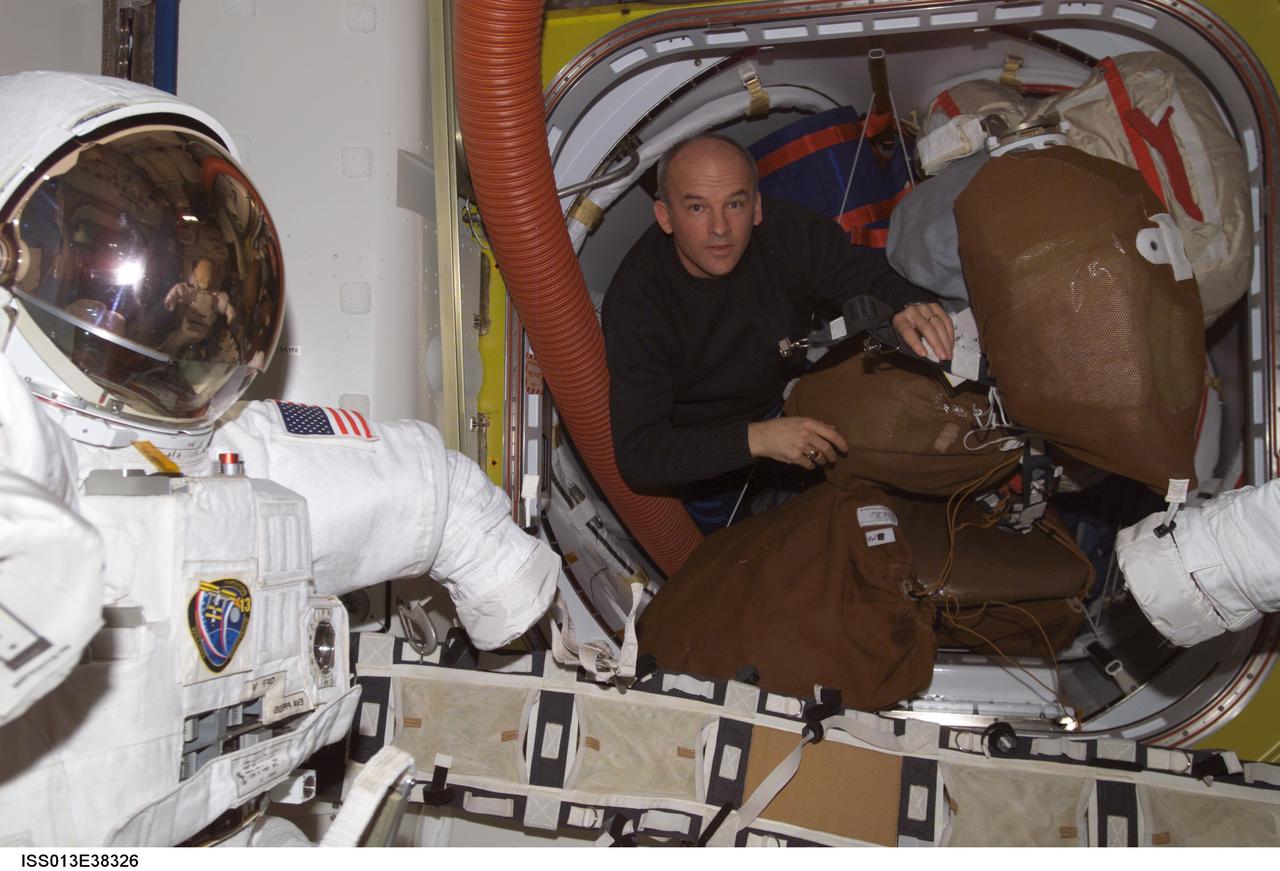 ISS013-E-38326 (17 June 2006) --- Astronaut Jeffrey N. Williams, Expedition 13 NASA space station science officer and flight engineer, works with stowage items as he performs routine housekeeping in the Quest Airlock of the International Space Station. An Extravehicular Mobility Unit (EMU) space suit is visible at left.