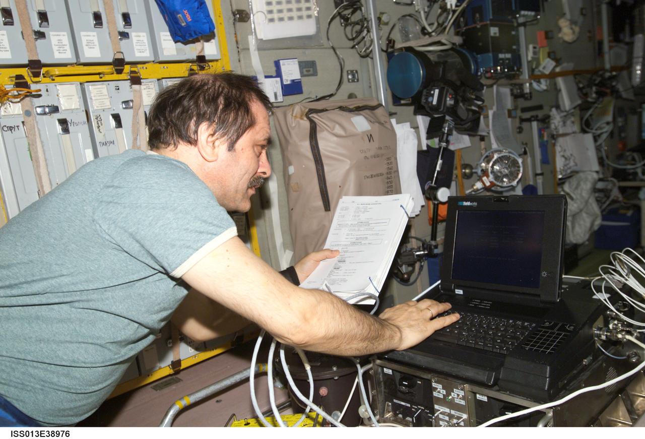 ISS013-E-38976 (21 June 2006) --- Cosmonaut Pavel V. Vinogradov, Expedition 13 commander representing Russia's Federal Space Agency, refers to a procedures checklist as he uses a computer in the Zvezda Service Module of the International Space Station.