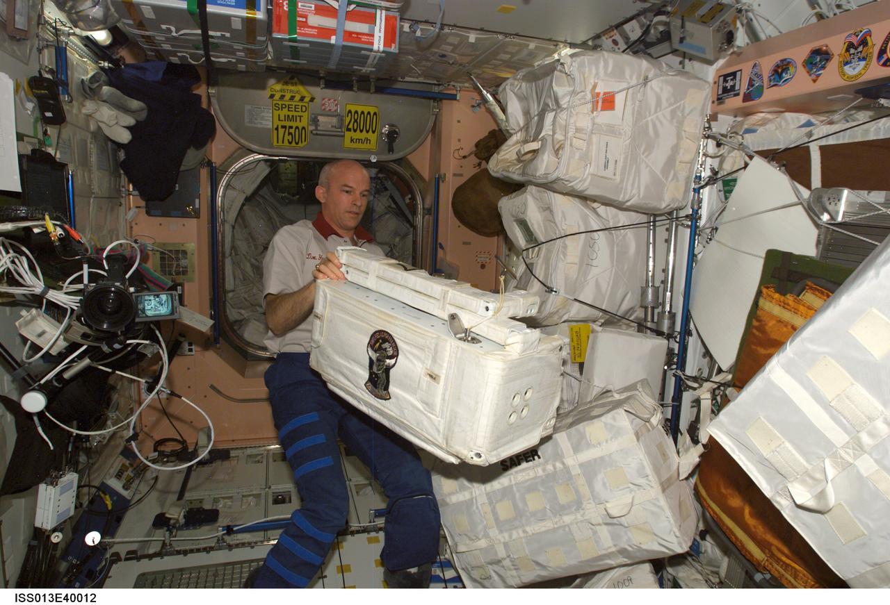 ISS013-E-40012 (22 June 2006) --- Astronaut Jeffrey N. Williams, Expedition 13 NASA space station science officer and flight engineer, works with stowage containers in the Unity node of the International Space Station.
