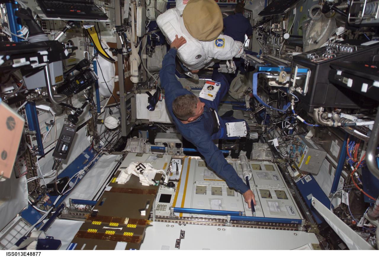 ISS013-E-48877 (6 July 2006) --- Astronaut Michael E. Fossum totes his extravehicular mobility unit space suit onboard the International Space Station a couple of days before he is to don it for a lengthy space walk. Fossum and his six Discovery crewmates are spending their first day on the orbital outpost.