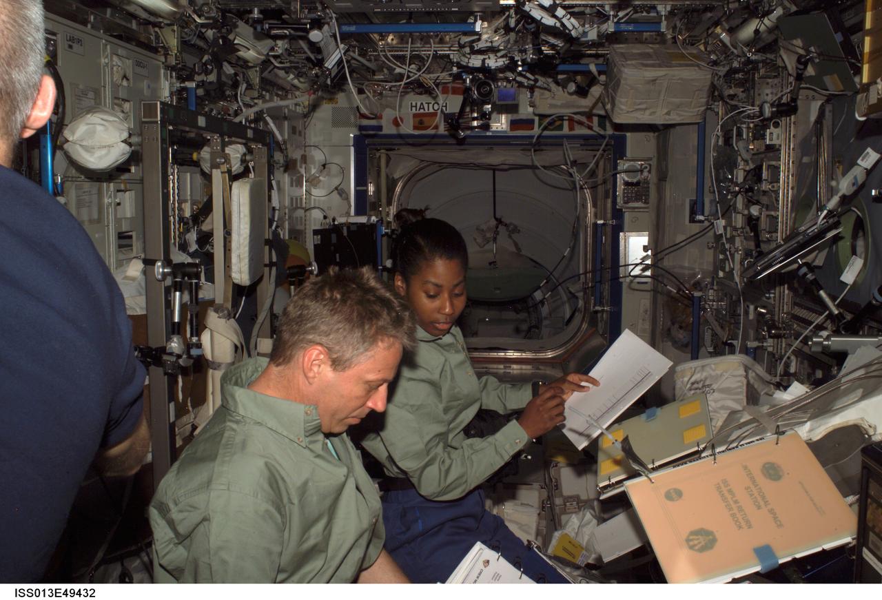 ISS013-E-49432 (9 July 2006) --- European Space Agency (ESA) astronaut Thomas Reiter (foreground) of Germany and astronaut Stephanie D. Wilson, STS-121 mission specialist, look over procedures checklists in the Destiny laboratory of the International Space Station.