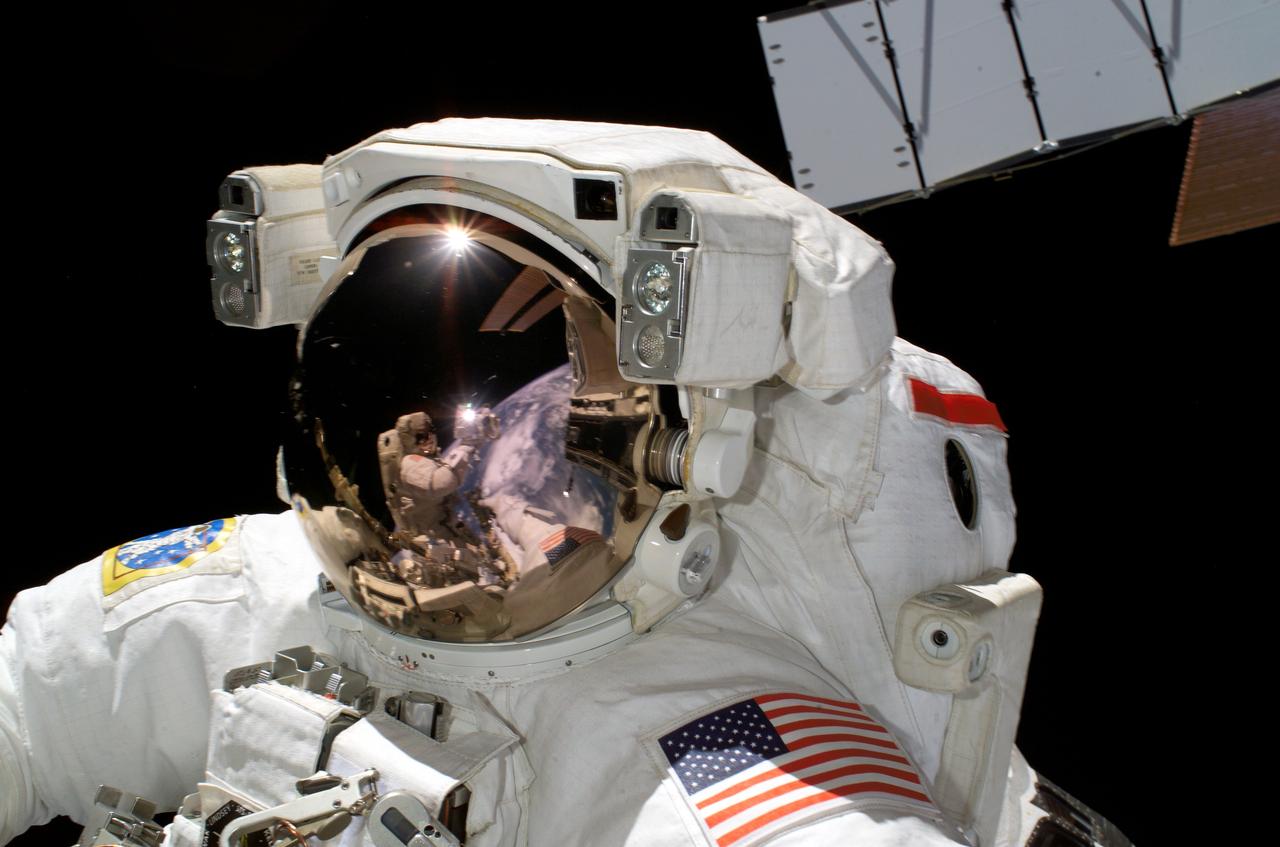 ISS013-E-49639 (8 July 2006) --- Astronaut Piers J. Sellers, STS-121 mission specialist, participates in the mission's first session of extravehicular activity (EVA) while Space Shuttle Discovery was docked with the International Space Station. Astronaut Michael E. Fossum, mission specialist, who was also on the spacewalk with Sellers and took this photo, appears as a small reflection in Seller's helmet visor. Earth's horizon and a portion of a station solar array are also visible in the reflection.