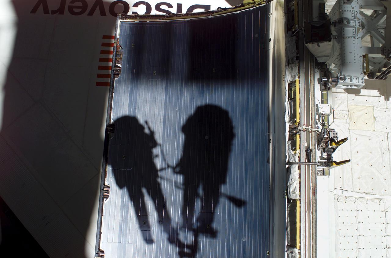 ISS013-E-49681 (8 July 2006) --- The shadows of astronauts Piers J. Sellers and Michael E. Fossum, STS-121 mission specialists, who are anchored to the Space Shuttle Discovery's Remote Manipulator System/Orbiter Boom Sensor System (RMS/OBSS) foot restraint, are visible against a shuttle's payload bay door during today's session of extravehicular activity (EVA).