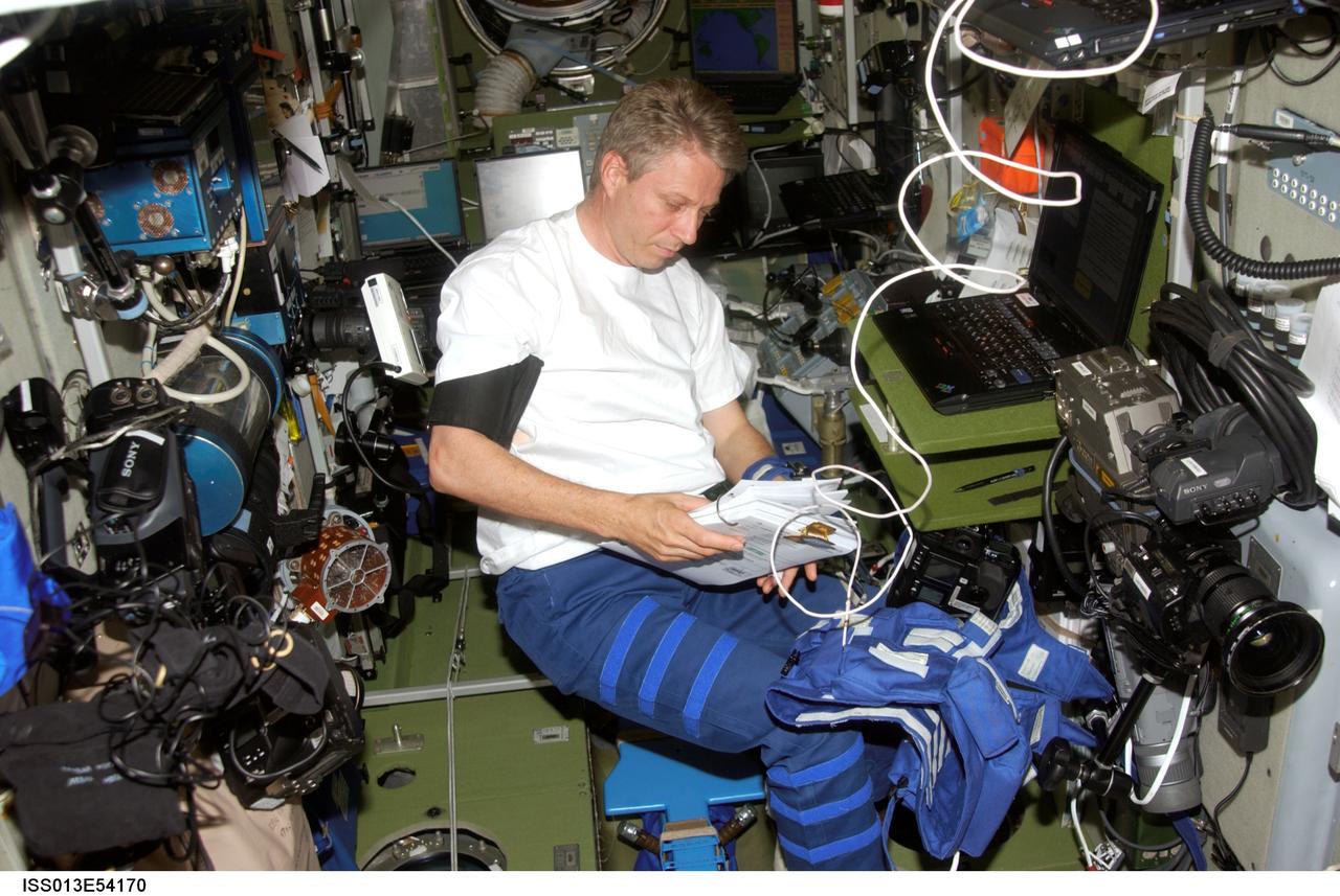 ISS013-E-54170 (July 2006) --- European Space Agency (ESA) astronaut Thomas Reiter, Expedition 13 flight engineer, looks over a procedures checklist in the Zvezda Service Module of the International Space Station.