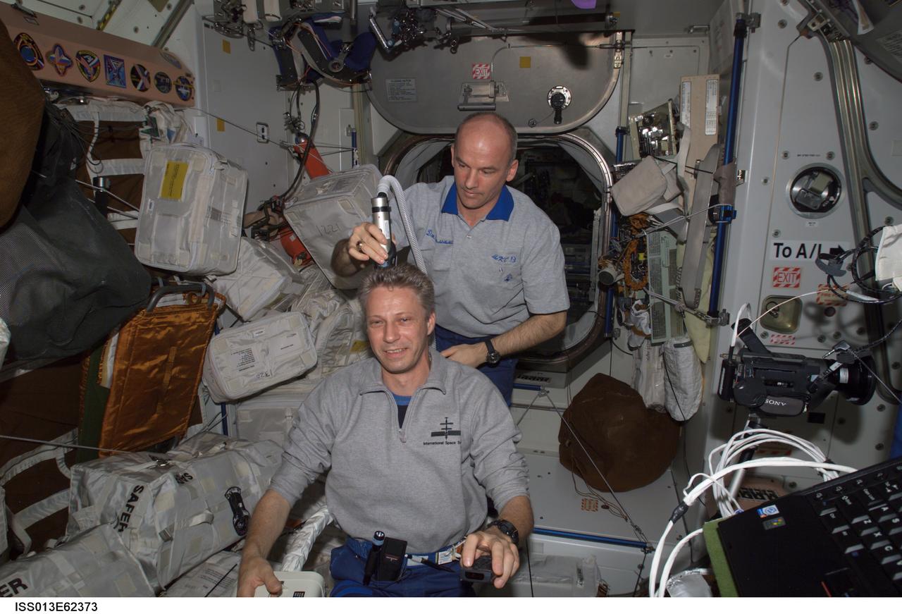 ISS013-E-62373 (29 July 2006) --- Astronaut Jeffrey N. Williams, Expedition 13 NASA space station science officer and flight engineer, trims astronaut Thomas Reiter's hair in the Unity node of the International Space Station. Williams used hair clippers fashioned with a vacuum device to garner freshly cut hair. Reiter, flight engineer, represents the European Space Agency (ESA).