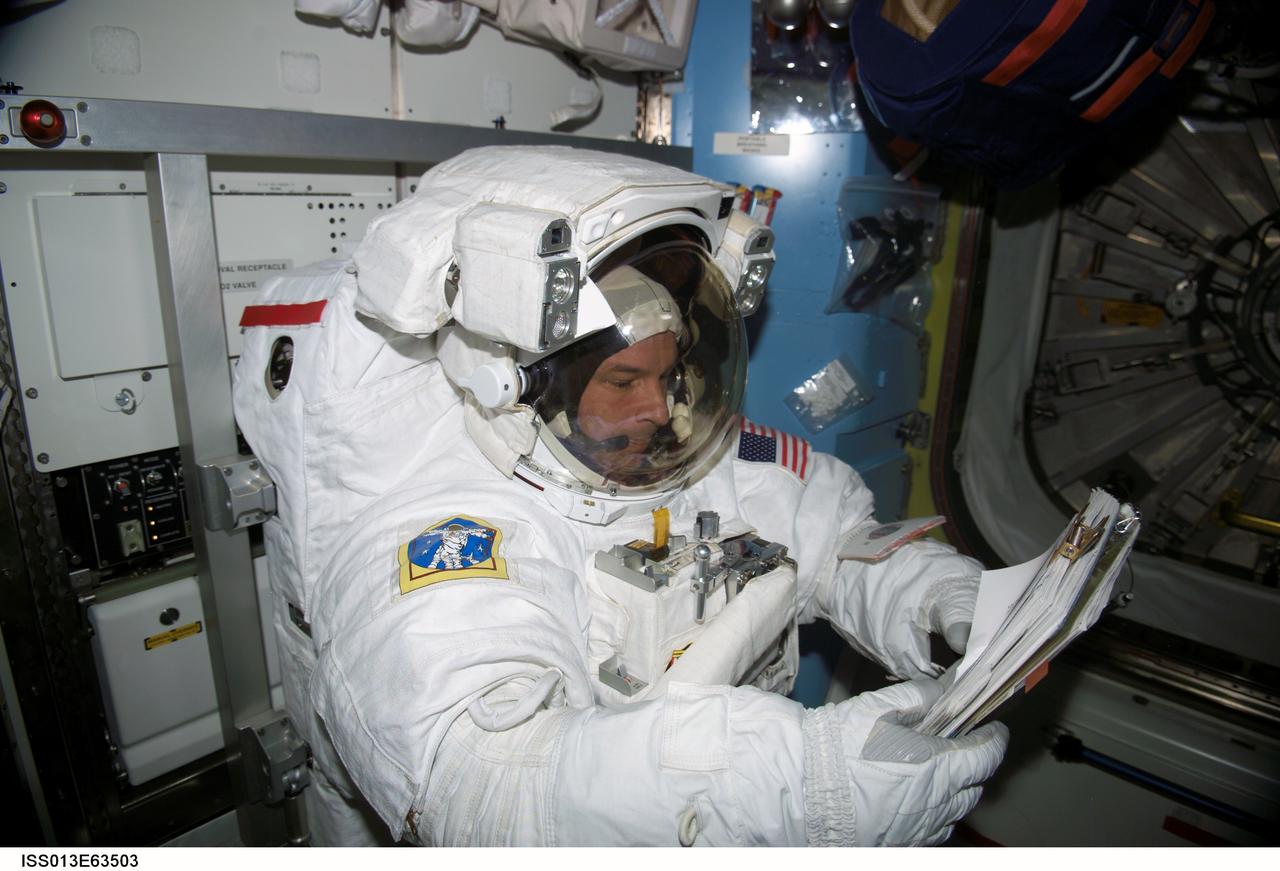 ISS013-E-63503 (3 August 2006) --- Astronaut Jeffrey N. Williams, Expedition 13 NASA space station science officer and flight engineer, brushes up on a task list prior to egressing a station airlock to go on to perform a 5-hour, 54-minute excursion which he shared with European Space Agency astronaut Thomas Reiter (out of frame). For part of the spacewalk, the pair worked closely in tandem, and then worked separately, getting ahead of their timeline, thus enabling the two to tack on extra tasks.