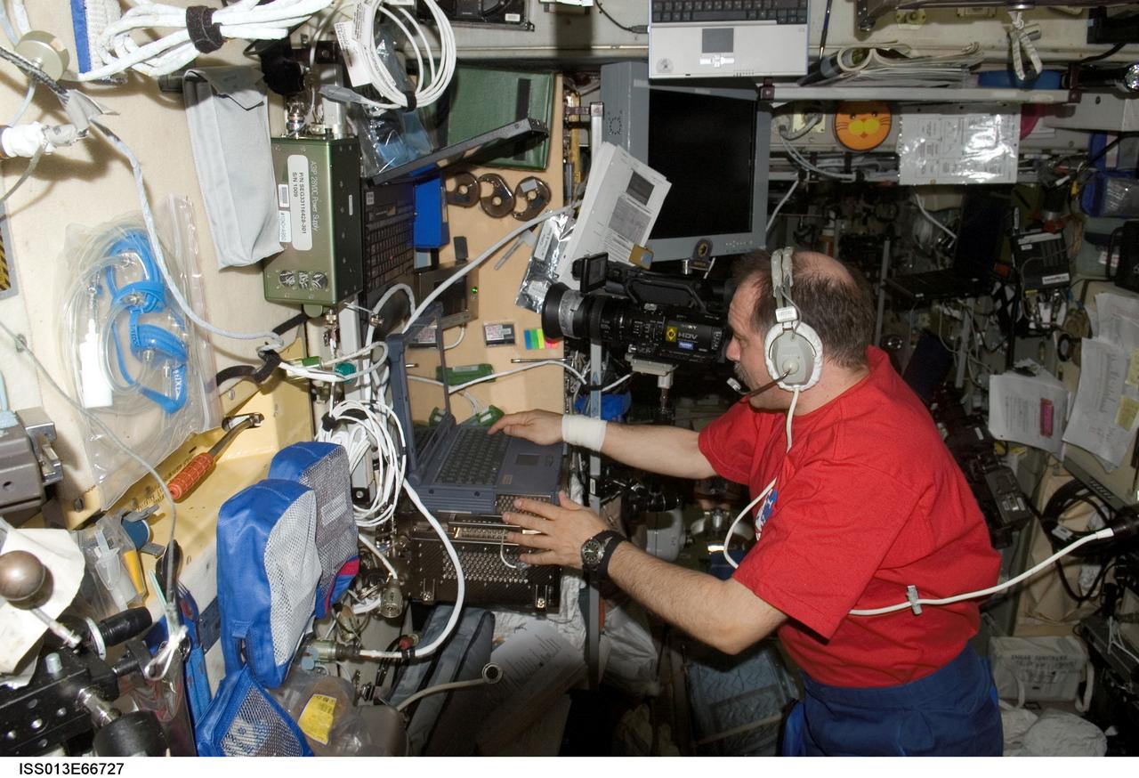 ISS013-E-66727 (August 2006) --- Cosmonaut Pavel V. Vinogradov, Expedition 13 commander representing Russia's Federal Space Agency, wears a communication system headset while using a video camcorder and computer in the Zvezda Service Module of the International Space Station.