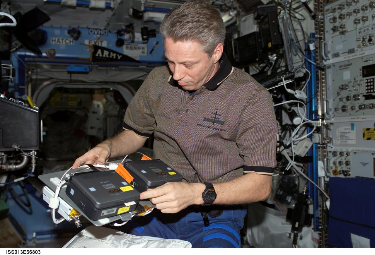ISS013-E-66803 (16 Aug. 2006) --- European Space Agency (ESA) astronaut Thomas Reiter, Expedition 13 flight engineer, works with a mini-digital video camera (DVCAM) and advanced video interface unit (AVIU)-CC VID cables in the Destiny laboratory of the International Space Station.