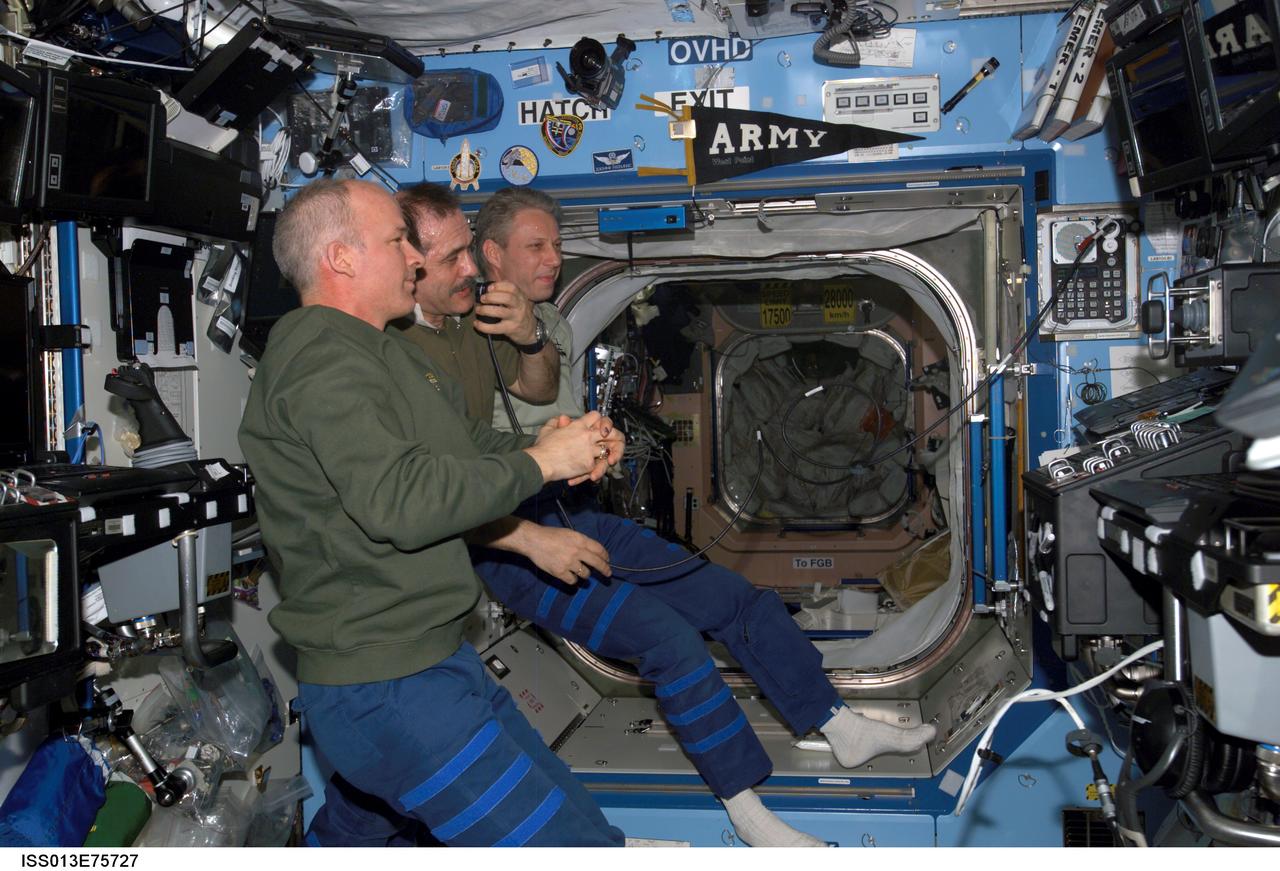 ISS013-E-75727 (31 Aug. 2006) --- Astronaut Jeffrey N. Williams (foreground), Expedition 13 NASA space station science officer and flight engineer; cosmonaut Pavel V. Vinogradov (center), commander representing Russia's Federal Space Agency; and European Space Agency (ESA) astronaut Thomas Reiter, flight engineer, conduct a teleconference in the Destiny laboratory of the International Space Station, via Ku- and S-band, with audio and video relayed to the Mission Control Center (MCC) at Johnson Space Center.