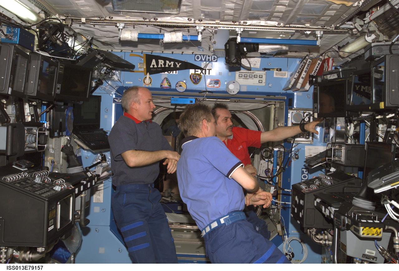 ISS013-E-79157 (9 Sept. 2006) --- Astronaut Jeffrey N. Williams (left), Expedition 13 NASA space station science officer and flight engineer; European Space Agency (ESA) astronaut Thomas Reiter (foreground), flight engineer; and cosmonaut Pavel V. Vinogradov, commander representing Russia's Federal Space Agency, discuss preparations for the arrival of the STS-115 crew in the Destiny laboratory of the International Space Station.