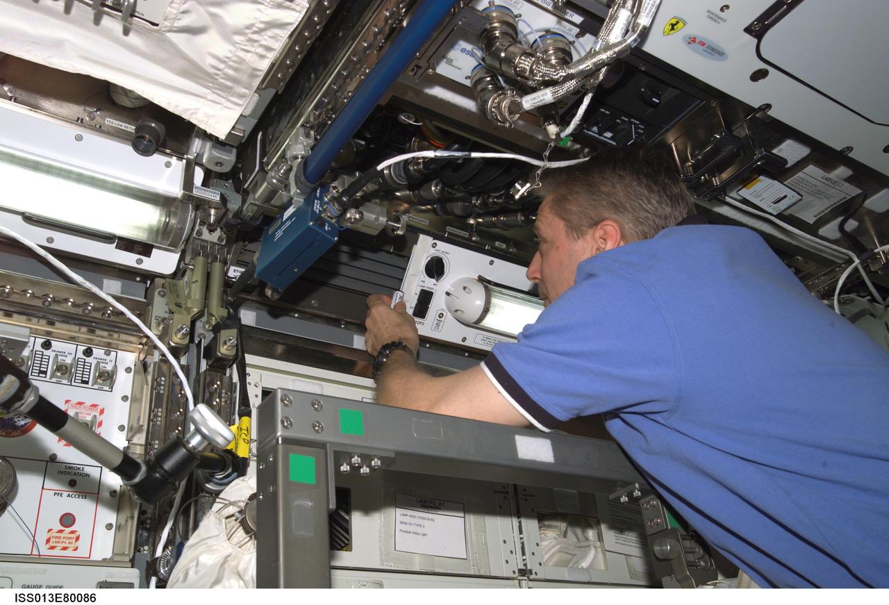 ISS013-E-80086 (10 Sept. 2006) --- European Space Agency (ESA) astronaut Thomas Reiter, Expedition 13 flight engineer, performs in-flight maintenance (IFM) on the lamp housing assembly (LHA) on LAB1P3 rack in the Destiny laboratory of the International Space Station.