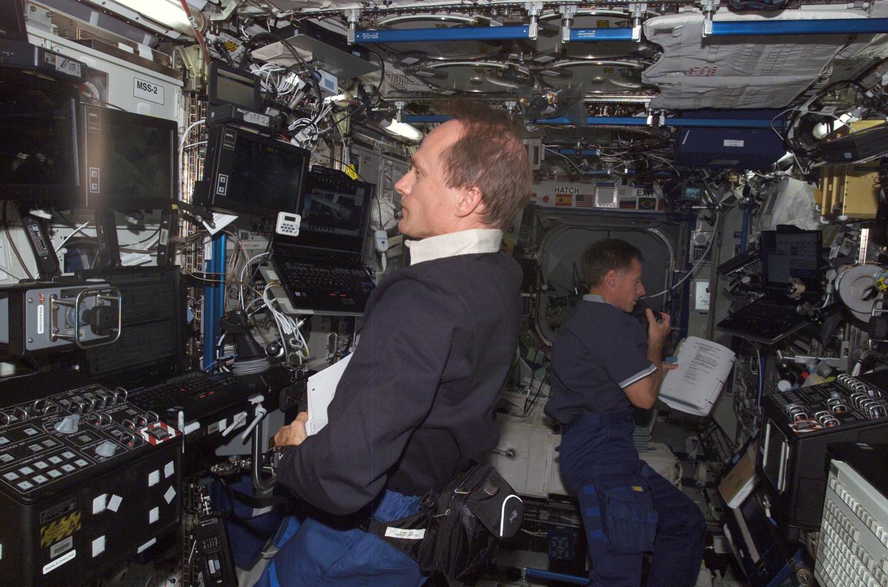 ISS013-E-80781 (12 Sept. 2006) --- Canadian Space Agency astronaut Steven G. MacLean, STS-115 mission specialist, and astronaut Christopher J. Ferguson, pilot, work inside the Destiny laboratory to support the first day of the resumption of construction on the International Space Station. Two crewmates--astronauts   Heidemarie M. Stefanyshyn-Piper and Joseph R. Tanner--earlier donned extravehicular mobility units and were outside now participating in the first of three scheduled space walks.