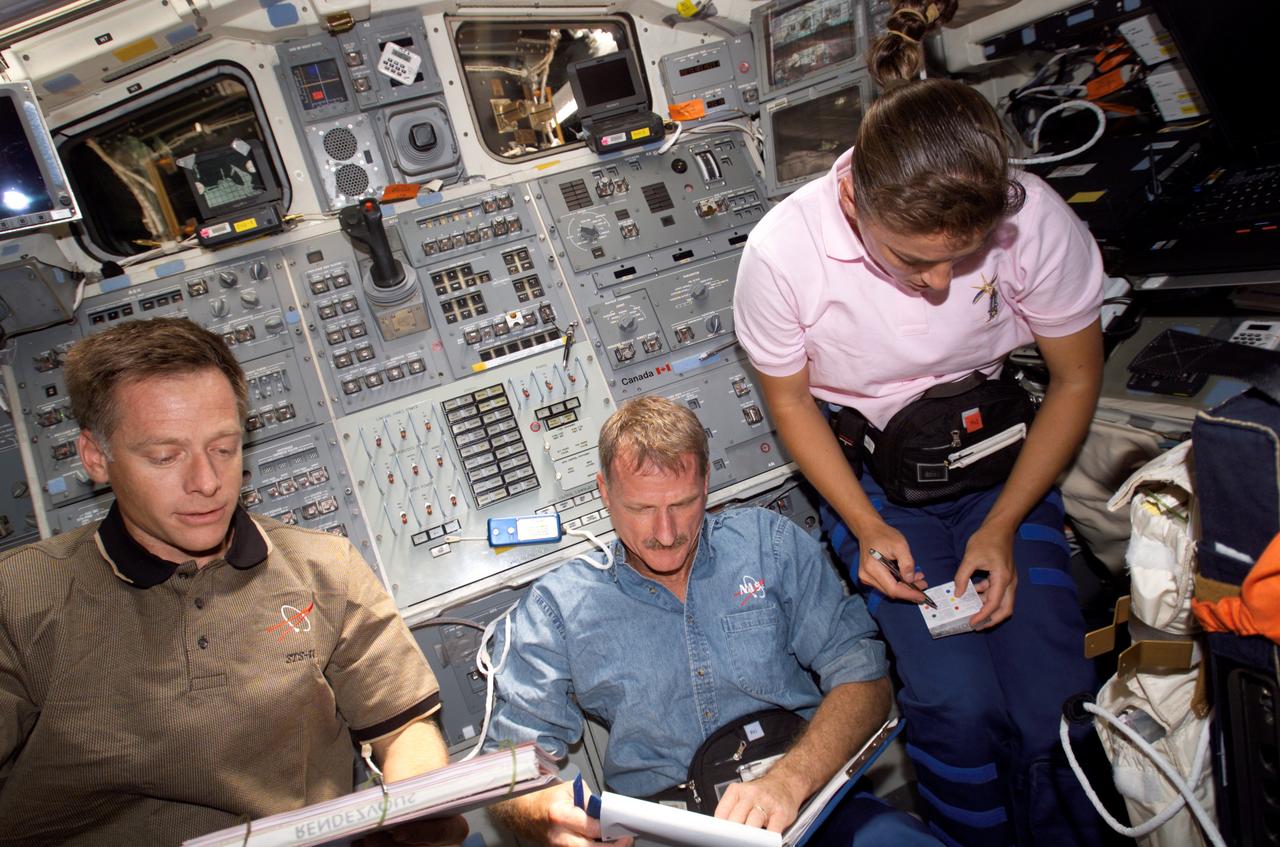 ISS013-E-82298 (17 Sept. 2006) --- Astronauts Christopher J. Ferguson (left), STS-115 pilot; Joseph R. Tanner and Heidemarie M. Stefanyshyn-Piper, both mission specialists, make preparations for their return home on the aft flight deck of the Space Shuttle Atlantis.