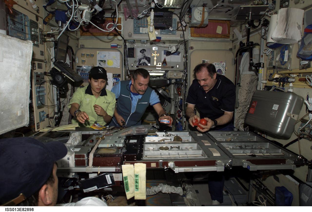ISS013-E-82898 (20 Sept. 2006) --- Spaceflight participant Anousheh Ansari (left), cosmonaut Mikhail Tyurin, Expedition 14 flight engineer representing Russia's Federal Space Agency; and cosmonaut Pavel V. Vinogradov, Expedition 13 commander representing Russia's Federal Space Agency, prepare to eat a meal at the galley in the Zvezda Service Module of the International Space Station.