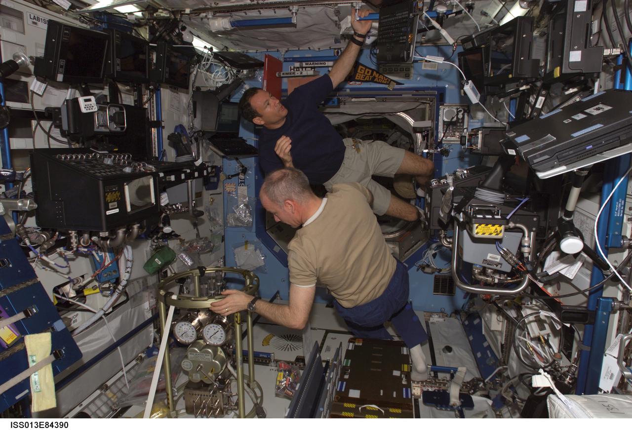 ISS013-E-84390 (27 Sept. 2006) --- Astronauts Jeffrey N. Williams (foreground), Expedition 13 NASA space station science officer and flight engineer, and Michael E. Lopez-Alegria, Expedition 14 commander and NASA space station science officer, work on the fluid servicing system installation in the Destiny laboratory of the International Space Station.