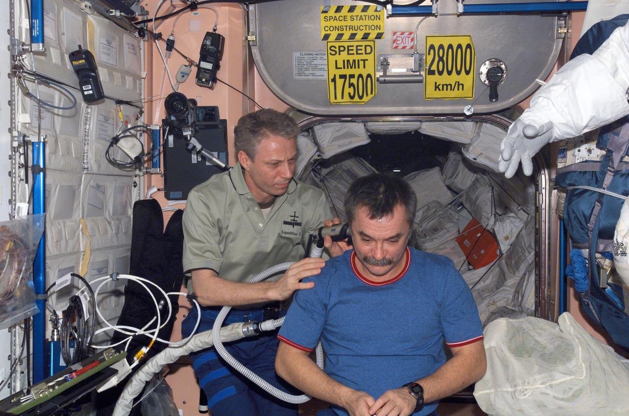 ISS014-E-07174 (5 Nov. 2006) --- European Space Agency (ESA) astronaut Thomas Reiter, Expedition 14 flight engineer, cuts the hair of cosmonaut Mikhail Tyurin, flight engineer representing Russia's Federal Space Agency, in the Unity node of the International Space Station. Reiter used hair clippers fashioned with a vacuum device to prevent freshly cut hair from being scattered throughout the module.