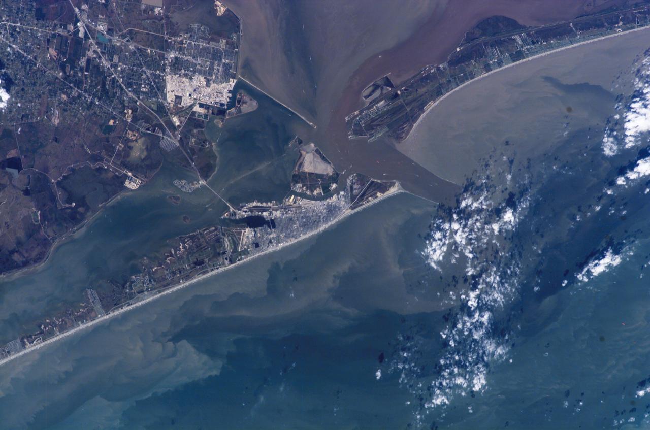 ISS014-E-07258 (4 Nov. 2006) --- Galveston, Texas is featured in this image photographed by an Expedition 14 crewmember on the International Space Station (ISS). Mexico established a port of entry (known as Galveston) in 1825, and following the Texas Revolution it was the capital of the Republic of Texas during 1836. The modern-day city of Galveston was incorporated in 1839, and became the major trading seaport of Texas during the latter half of the 19th century. The city was largely destroyed in early September of 1900 by a powerful hurricane; this, coupled with construction of the Houston Ship Channel and discovery of oil in eastern Texas shifted the center of trade northwest to Houston. Many human footprints are easily observed from the vantage point of low Earth orbit. The eastern half of Galveston Island is dominated by the city of Galveston (gray-white region at center). A large seawall along the Gulf of Mexico (southern coastline of Galveston Island) protects most of the city. To the west of Galveston, coastal wetlands are largely submerged by regional subsidence--a result of ground water withdrawal by the petrochemical industry of Houston and Texas City. The entrance to Galveston Bay and the Houston Ship Channel is located between Galveston Island and the Bolivar Peninsula (upper right). Numerous ship wakes are visible along the Houston Ship Channel. Other visible features of the entrance to Galveston Bay include the five-mile long Texas City Dike, a structure that protects the Texas City channel and includes a fishing pier that extends 600 feet beyond the end of the Dike. Extensive petroleum processing facilities are located to the west of the Dike in Texas City. The Intracoastal Waterway runs through western Galveston Bay; new subdivisions built on dredge spoils are visible along the northern boundary of the Waterway. Geologists studying the ISS collection of down linked still imagery observe that complex estuarine sediment patterns are visible in this image. Dark brown to tan waters adjacent to the Bolivar Peninsula and Texas City Dike reflect increased sediment loads following heavy rains in mid-to-late October, coupled with northerly winds moving Bay water southwards. Turbidity currents to both the northwest and southeast of Galveston Island produce a more chaotic pattern of sediment-laden (light green to tan) and relatively sediment-free (dark green) water leading into the dark green Gulf of Mexico (lower right).