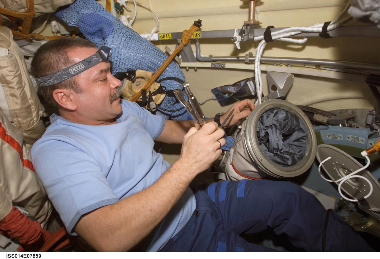 ISS014-E-07859 (14 Nov. 2006) --- Cosmonaut Mikhail Tyurin, Expedition 14 commander representing Russia's Federal Space Agency, works with a sleeve of a Russian Orlan spacesuit in the Pirs Docking Compartment of the International Space Station.