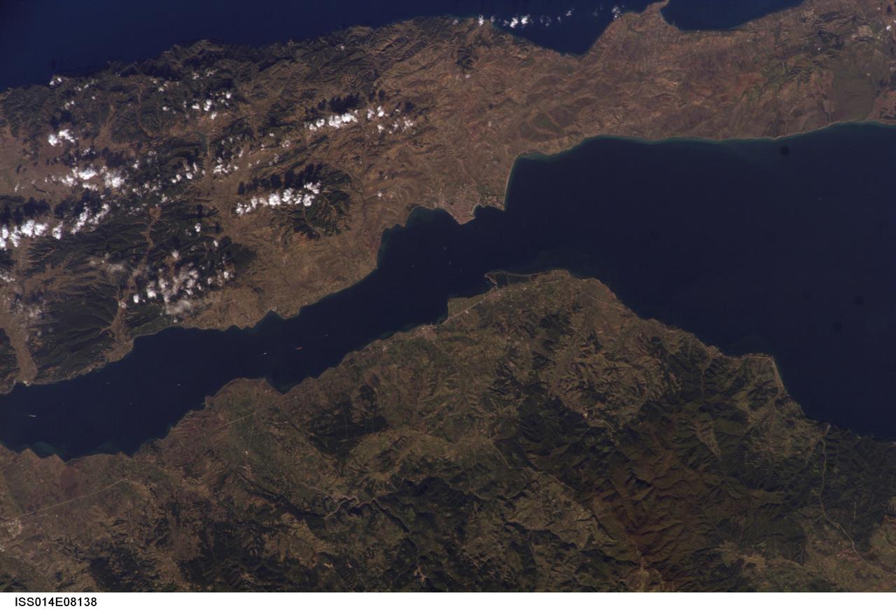 ISS014-E-08138 (9 Nov. 2006) --- Gallipoli and Dardanelles Strait, Turkey are featured in this image photographed by an Expedition 14 crewmember on the International Space Station. The city of Gallipoli (or Gelibolu in Turkish) sits at a crossroads between the Marmara and Aegean Seas, connected by the Dardanelles Strait. According to scientists, the strait is a 61 kilometer-long drowned fault valley formed during tectonic activity during the Tertiary period as the Arabian, Indian, and African plates collided with the Eurasian plate. This faulting, which formed the great mountain ranges of the Alps and Himalayas, also created the rugged terrain of western Turkey visible in the lower half of this image. Plate collision continues today, leading to frequent strike-slip (side-by-side relative motion along a fault, rather than up or down motion) earthquakes in the region as Turkey moves westward in relation to Eurasia (sometimes called escape tectonics). The urbanized area of modern Gallipoli is visible as a light gray to pink region at the entrance to the Dardanelles Strait. Water in the Strait flows in both northeast and southwest directions due to opposite surface and undercurrents. Several ships are visible in the Strait to the southwest of Gallipoli (center left).